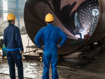 Workers supervising the manufacture of a metallic cylinder